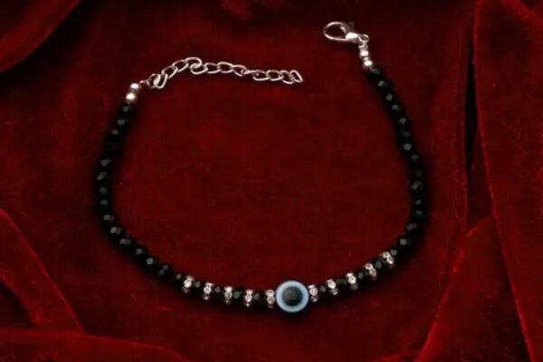 Black Evil Eye Bracelet with silver plating displayed on a vibrant red background, highlighting the elegant design and intricate charm.