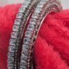 Silver-Plated Bangles Set adorned with cubic zirconia, displayed on a vibrant red background to enhance its elegance and intricate design.