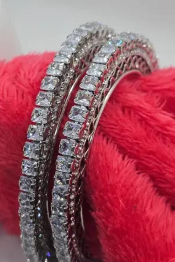 Silver-Plated Bangles Set adorned with cubic zirconia, displayed on a vibrant red background to enhance its elegance and intricate design.