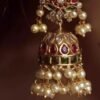 Model wearing gold-plated matte finish jhumka earrings with multicolor Kundan stones and pearls, highlighting their ethnic elegance
