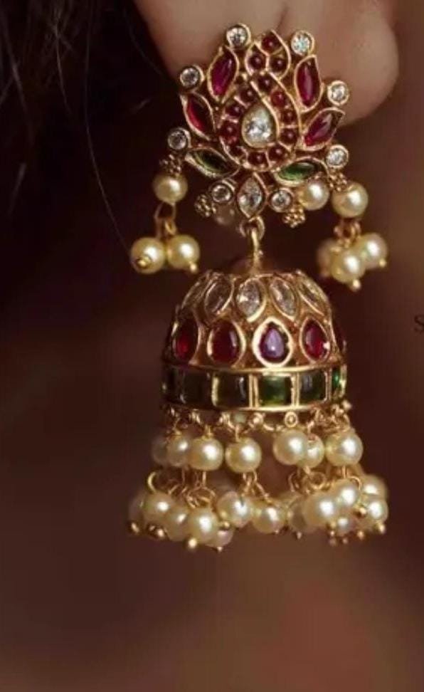 Model wearing gold-plated matte finish jhumka earrings with multicolor Kundan stones and pearls, highlighting their ethnic elegance